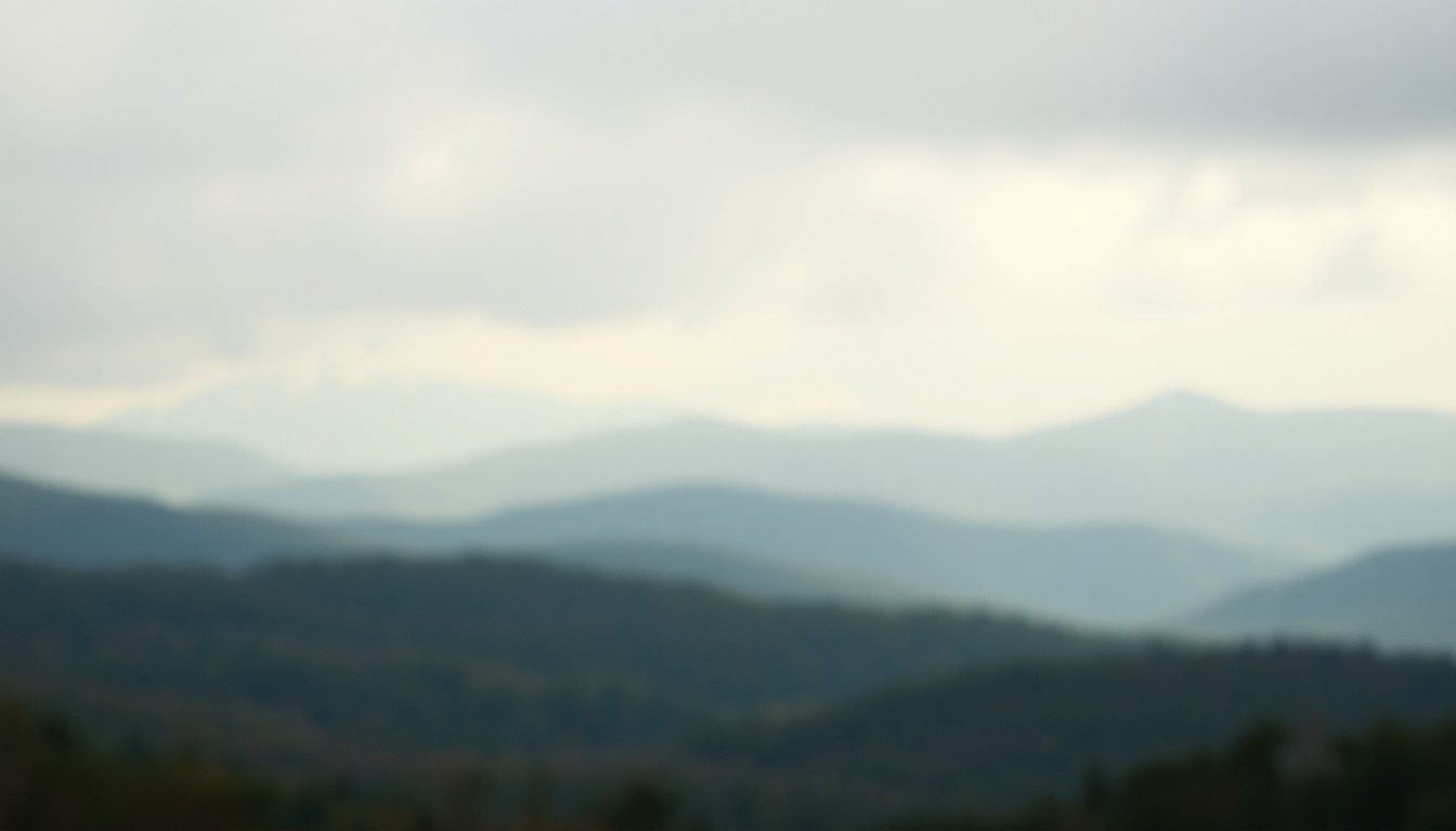 An extremely blurred, atmospheric photograph depicting a hazy landscape of rolling hills and forests in muted shades of green, brown, and blue, evoking the tranquil Adirondack setting that influenced the life and work of the abolitionist John Brown.