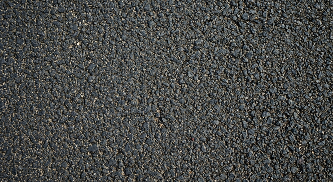 An extreme close-up of the rough, pebbled surface of asphalt road pavement, capturing the intricate patterns and colors in a dramatic, artistic manner.